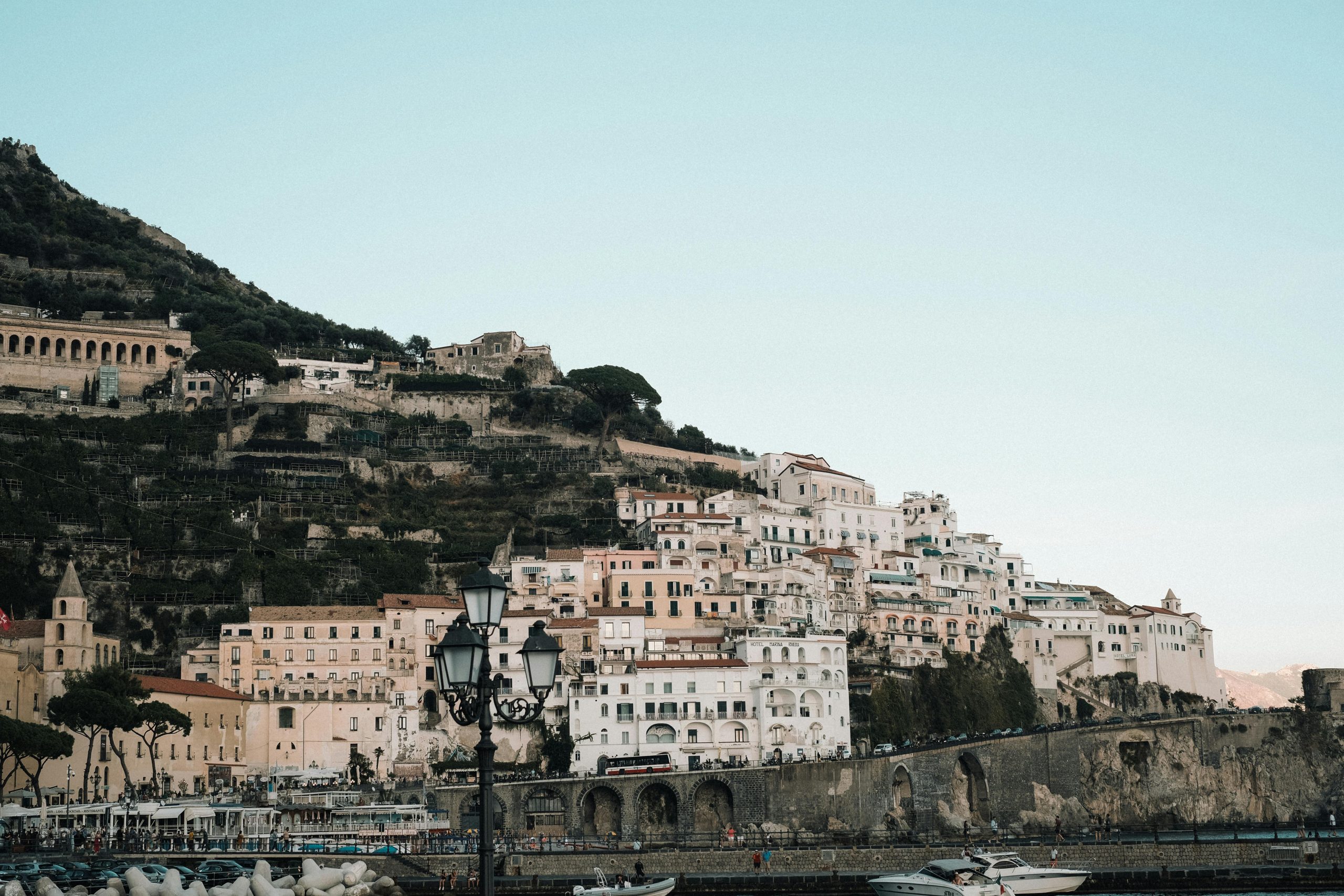 services-01 A picturesque view of a coastal town on the Amalfi Coast with hillside buildings and boats in the harbor.